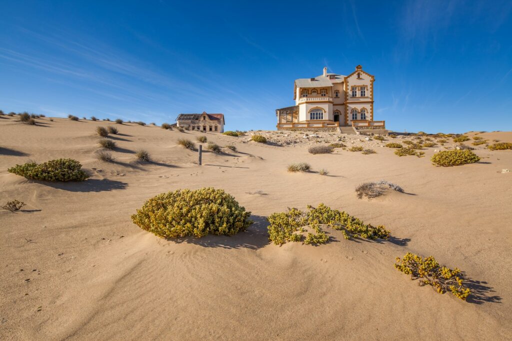 Historic abandoned house half-buried in sand dunes at Kolmanskop ghost town near Luderitz, Namibia