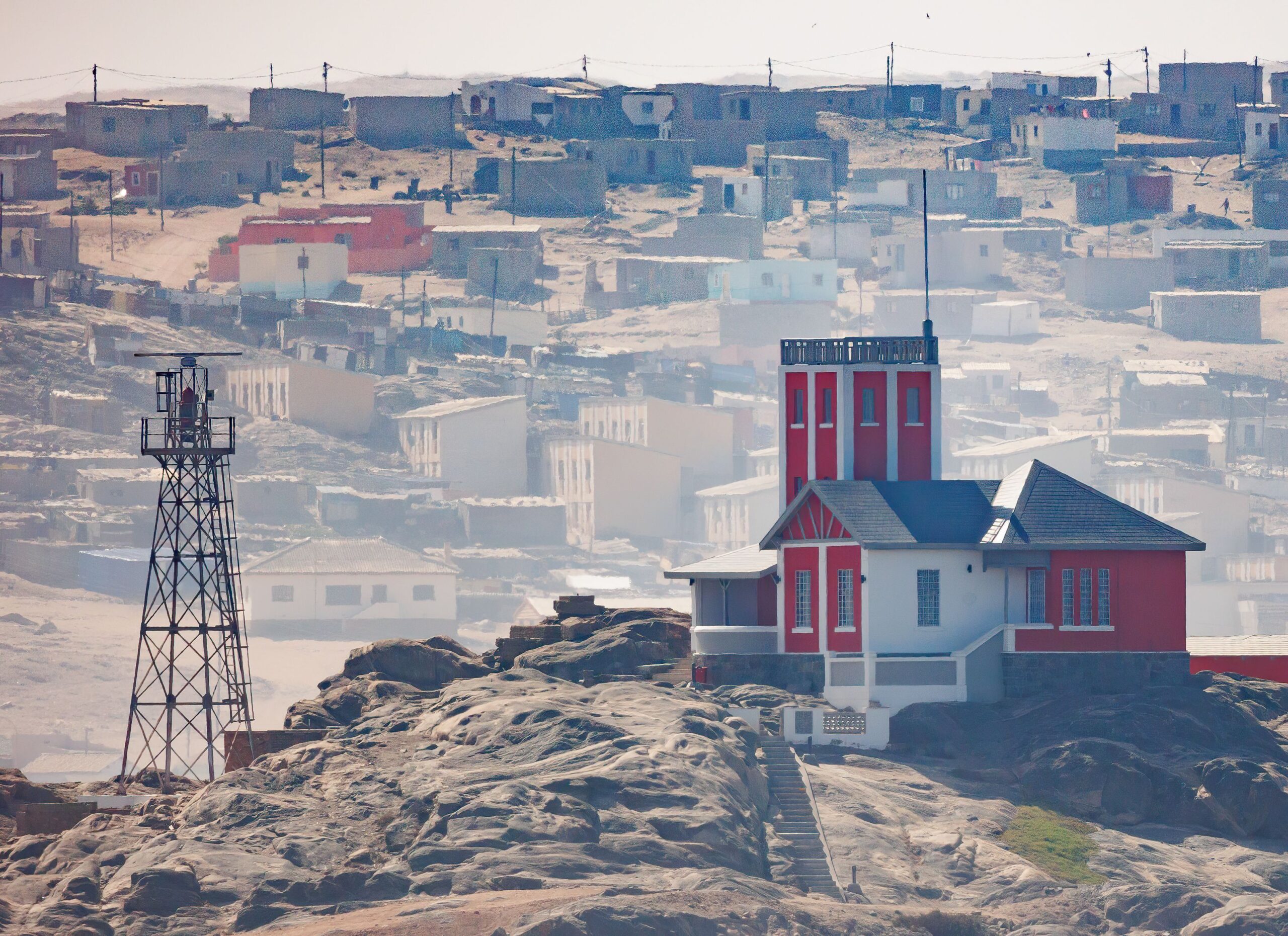 Une tour de guet et un bâtiment d’époque coloniale sur les rochers au-dessus de Luderitz, en Namibie, avec la ville dans la brume côtière