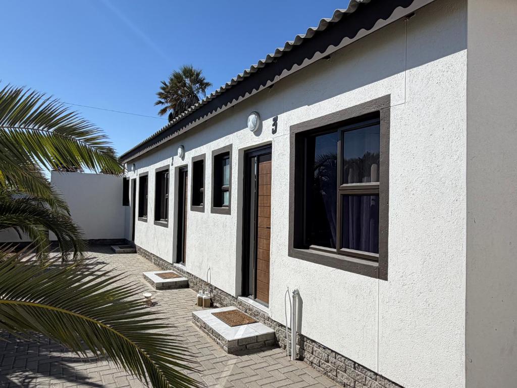Coastwave Guesthouse, Уолфиш-Бей: гостевой дом снаружи с пальмой