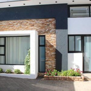 Deluxe Residence, Windhoek — brick house with black windows and flowers