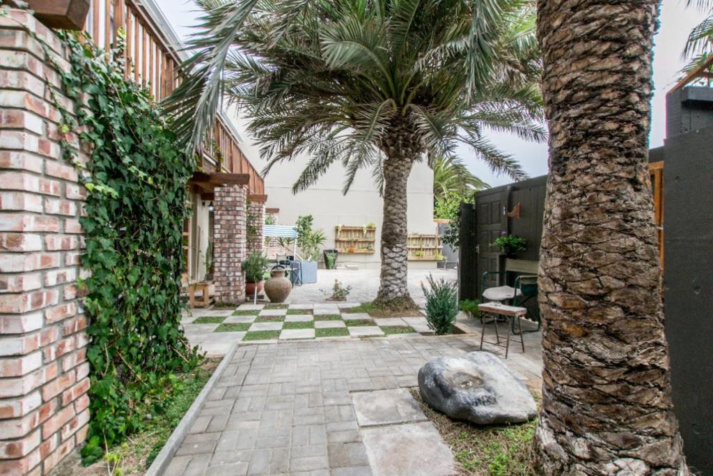 Namibia Nights Accommodation Swakopmund: palm-lined courtyard and brick building