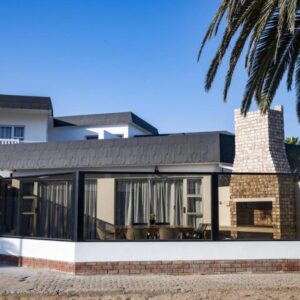 Poseidon Beachfront Holiday Home Swakopmund: exterior de la casa con puertas de cristal y palmera