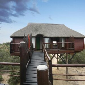 Stiltz Guest House, Swakopmund : chalet sur pilotis et passerelle en bois près de la plage